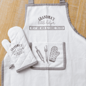 A white apron and oven mitt with an oven mitt, spatula and rolling pin.