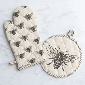 A pair of oven mitts and pot holder with bees.