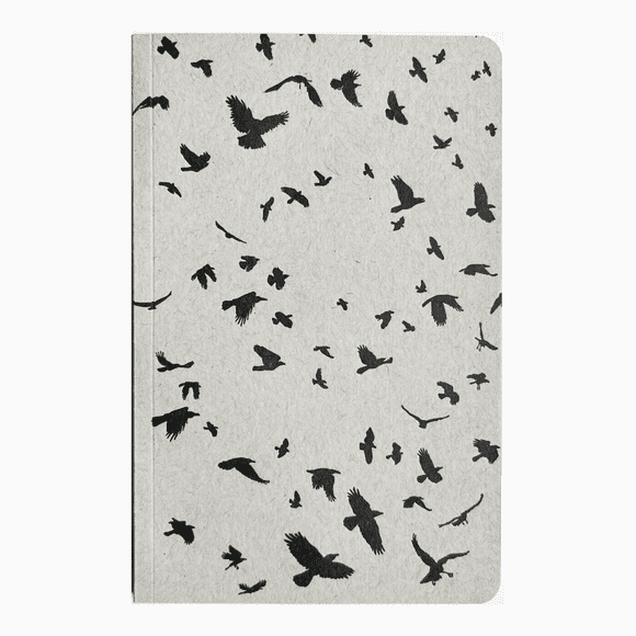 A notebook with black birds flying around it.