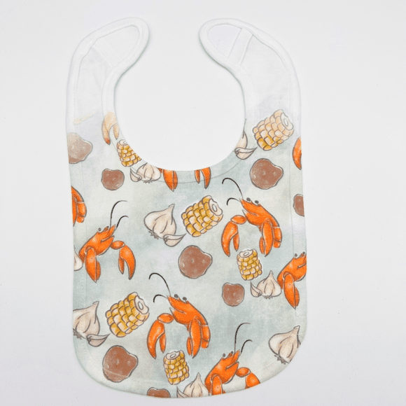 A lobster bib with shells and crackers on it.