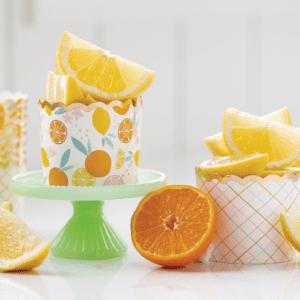 A table with two cakes and three cups of orange slices.