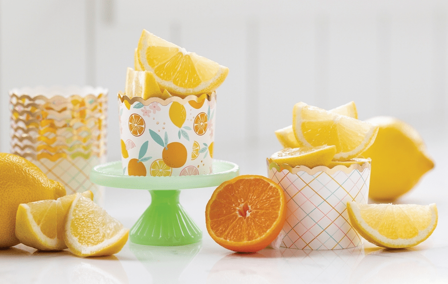 A table with two cakes and three cups of orange slices.