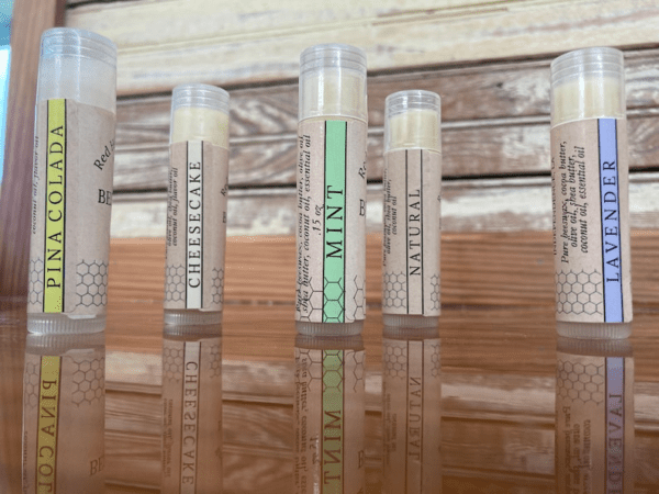 Five flavored lip balm tubes on wood.