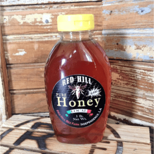 A bottle of honey sitting on top of a wooden table.