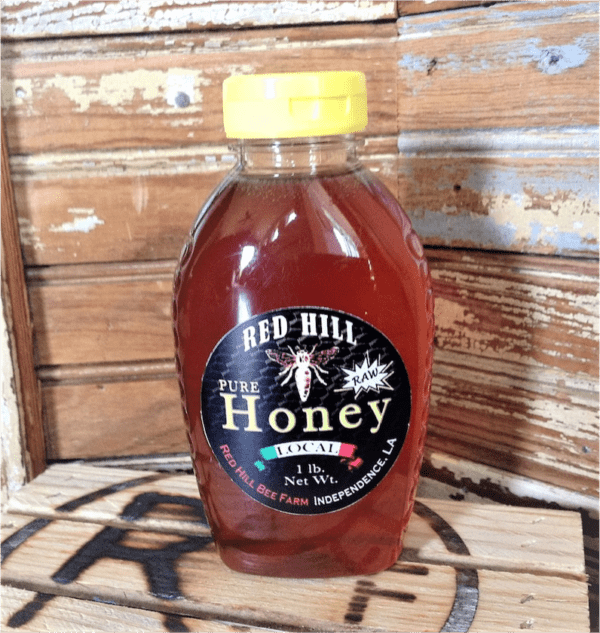 A bottle of honey sitting on top of a wooden table.