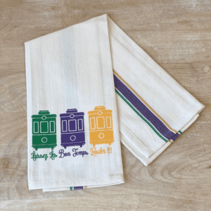 White kitchen towel with Mardi Gras streetcar design.