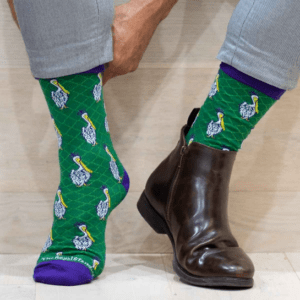 A person wearing green socks with blue and yellow designs.