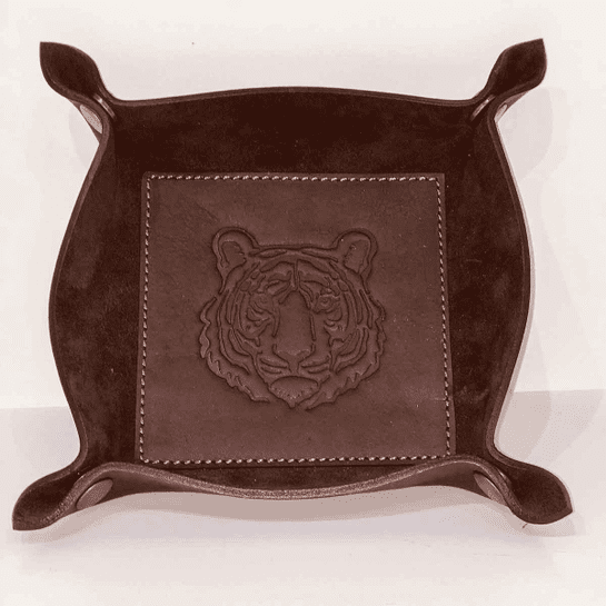 A brown leather tray with a tiger head on it.