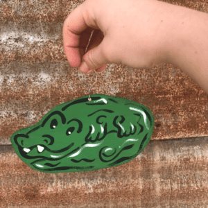 A hand holding onto an alligator shaped object.