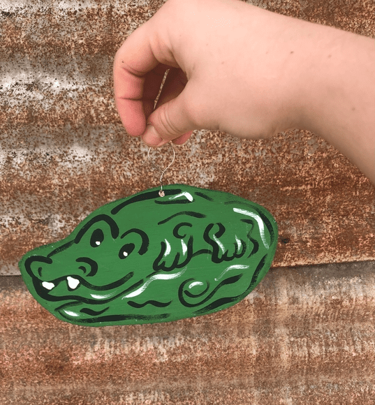 A hand holding onto an alligator shaped object.