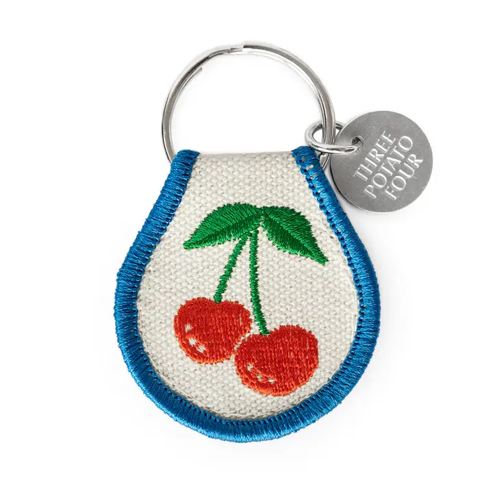 White keychain with blue border and cherries.