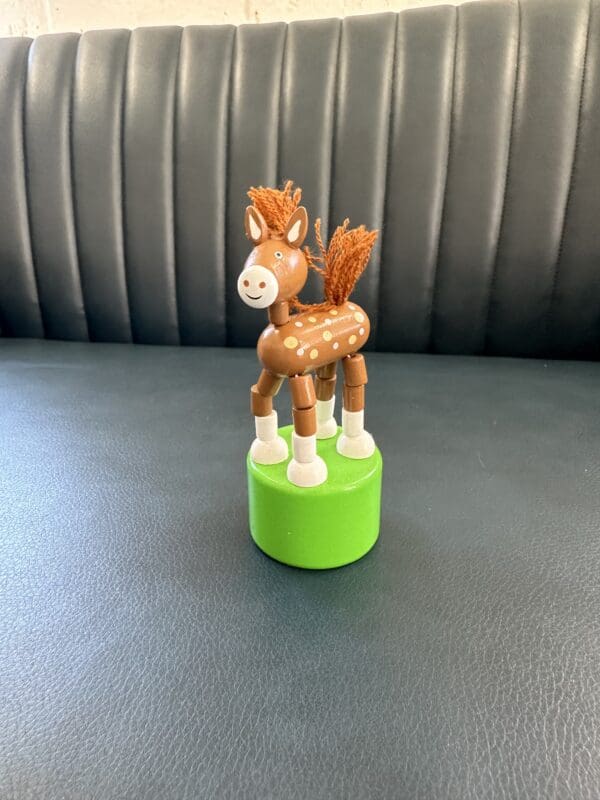 Wooden toy horse on a green base.