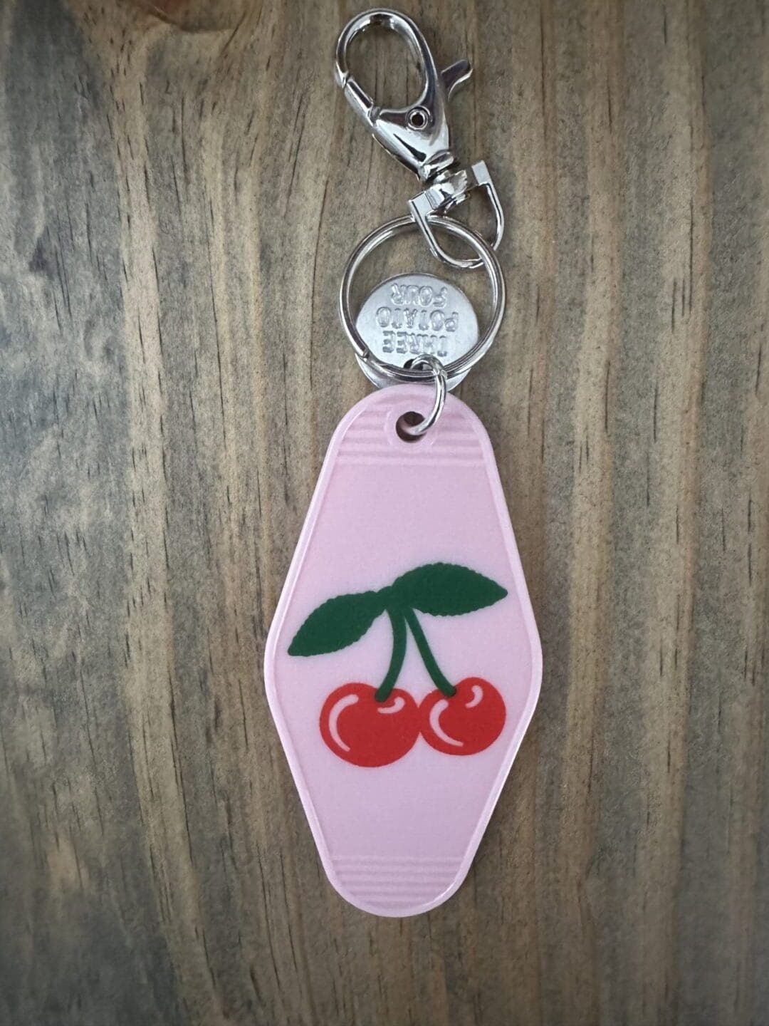 Pink motel key chain with cherries.