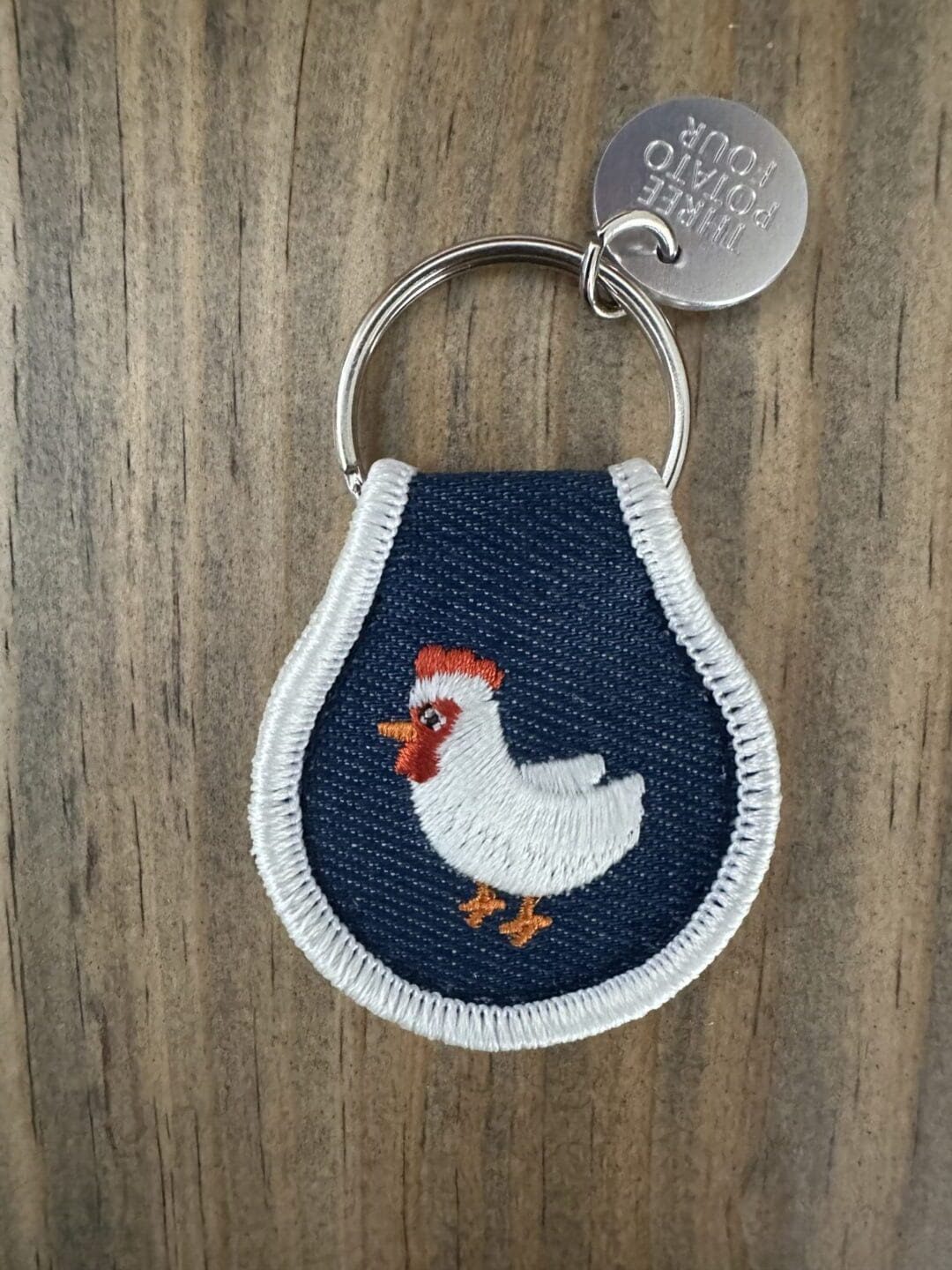 Keychain with embroidered white chicken.