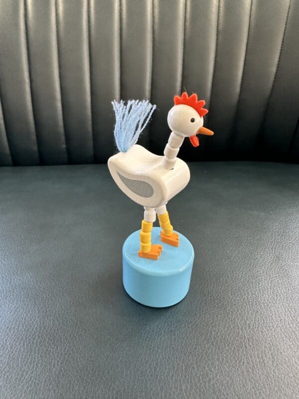 Wooden toy chicken on a blue base.