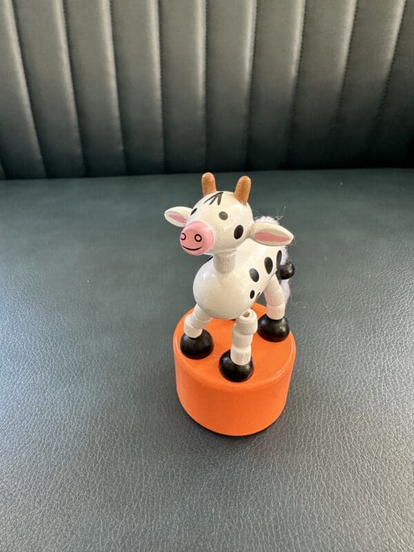 Wooden cow toy on orange base.