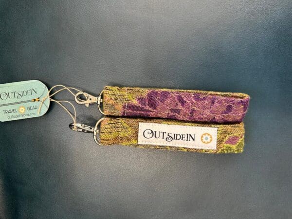 Purple and green fabric key chain with brand name.