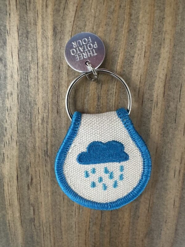 Keychain with blue rain cloud embroidery.