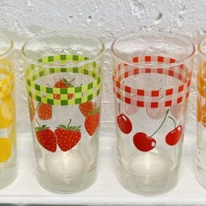 Four fruit-themed glasses; lemons, strawberries, cherries, oranges.
