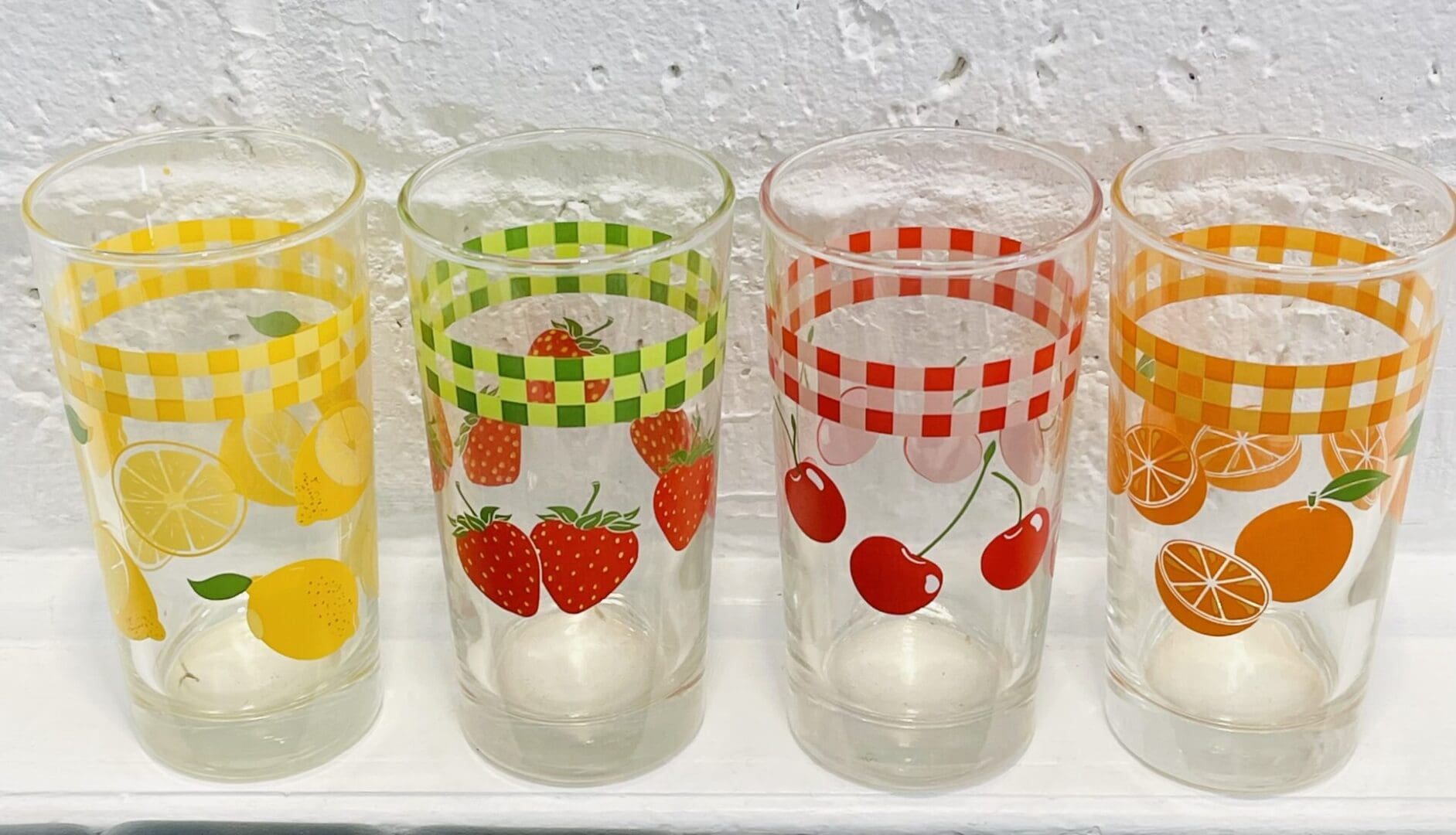 Four fruit-themed glasses; lemons, strawberries, cherries, oranges.